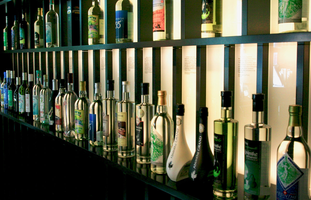 Swiss absinthe bottles lined up on the lit shelves of the Maison de l’Absinthe bar