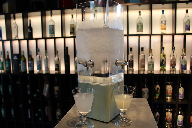 Deux verres d’absinthe louchée, une blanche et une verte, devant une fontaine au bar de la Maison de l’Absinthe