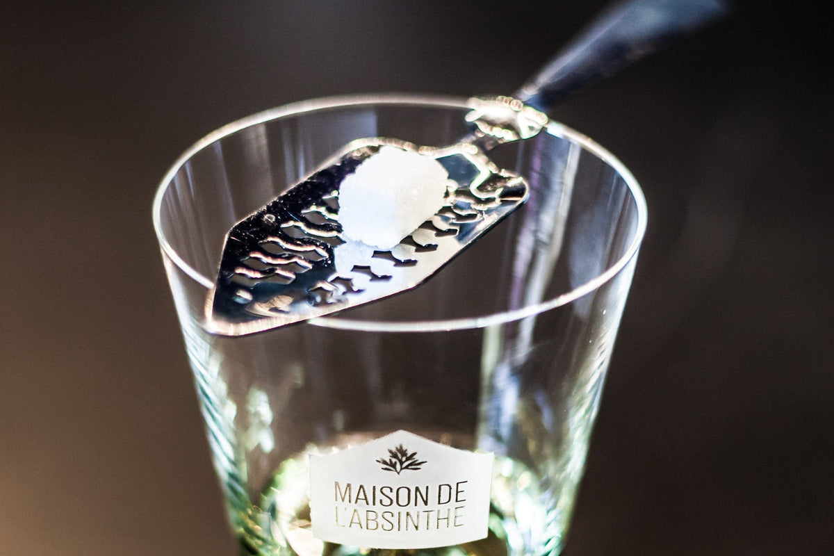 Absinthe Glass and Absinthe spoon with sugar over an absinthe verte