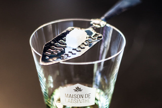 Absinthe Glass and Absinthe spoon with sugar over an absinthe verte