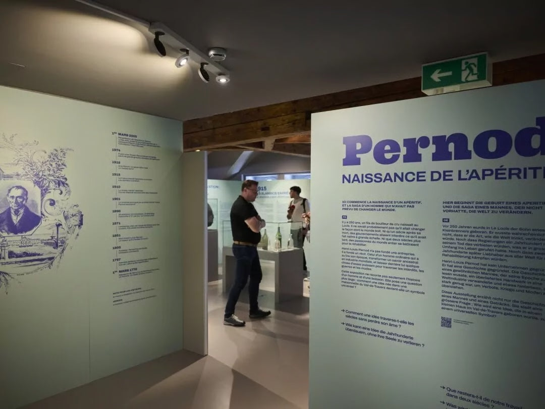 The Pernod exhibition entrance: a wall reading "Pernod, naissance de l'apéritif" beside a chronological frieze, visitors inside