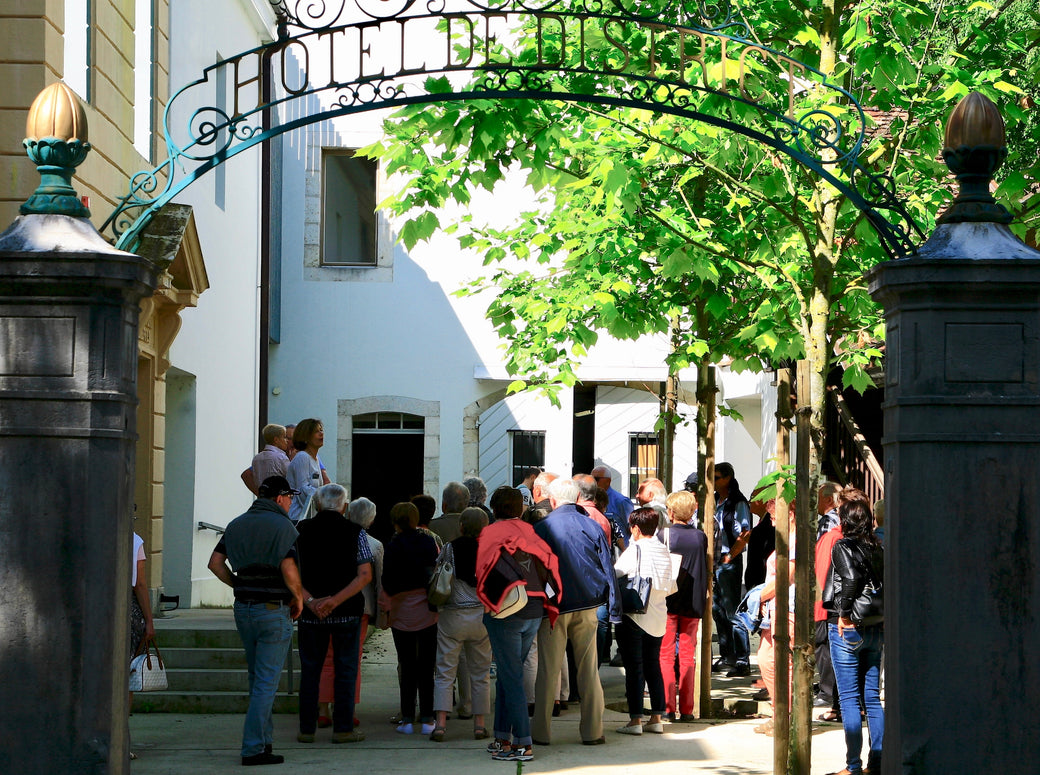 A group of visitors gathering under the archway of the Maison de l'Absinthe