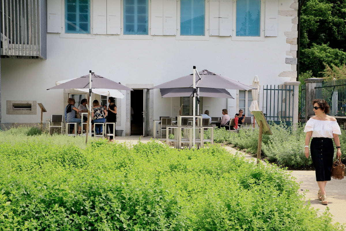 Aerial view of the Maison de l'Absinthe garden with visitors under grey parasols