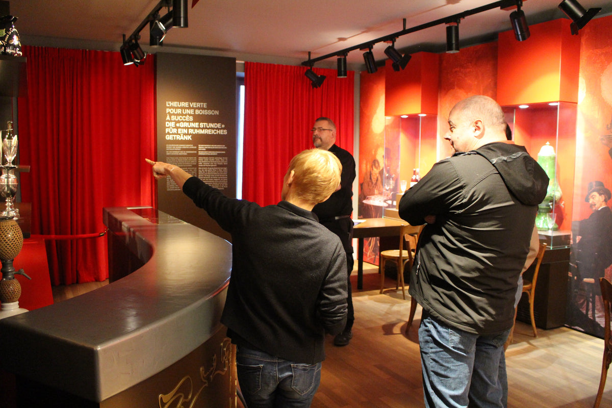 Museum guide leading a group through the absinthe exhibition in the red salon