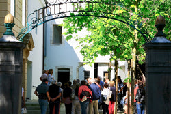 Group of visitors at the iron entrance gate of the Maison de l'Absinthe museum
