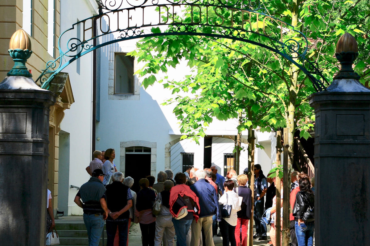 Group of visitors at the iron entrance gate of the Maison de l'Absinthe museum